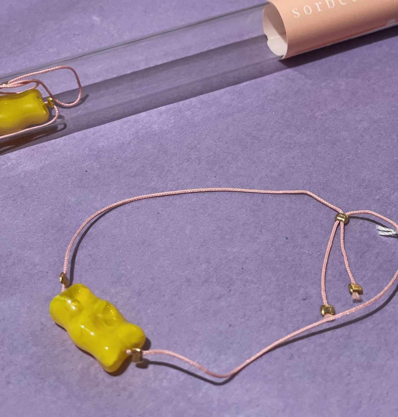 Armband Gummibärchen gelb mit rosa Band, verpackt im Reagenzglas