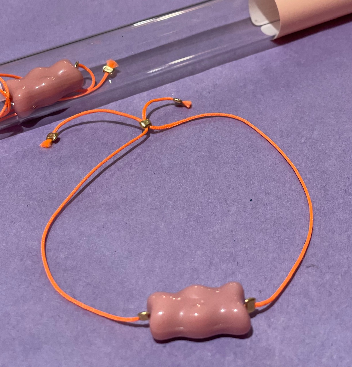 Armband Gummibärchen rosa mit neon orangefarbenen Band, verpackt im Reagenzglas
